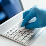 closeup-shot-person-sanitizing-laptop-s-keyboard