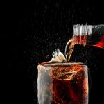 pour-soft-drink-in-glass-with-ice-splash-on-dark-background