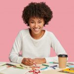 positive-female-illustrator-makes-sketches-with-crayon-on-blank-sheet-of-paper