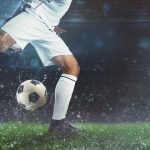 close-up-of-a-soccer-scene-at-night-match-with-player-in-a-white-uniform-kicking-the-ball-with-power